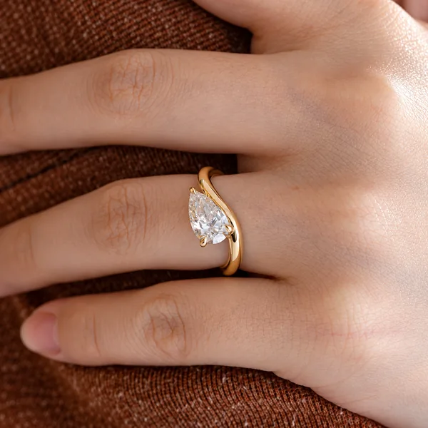 Yellow gold ring with a pear-shaped clear stone held by prongs.