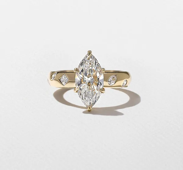 Yellow gold ring with a prong-set marquise center stone and small geometric accents.