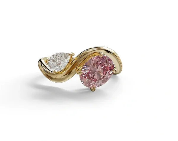 A yellow-gold twist ring with a large pink round stone and a smaller clear pear-shaped stone.