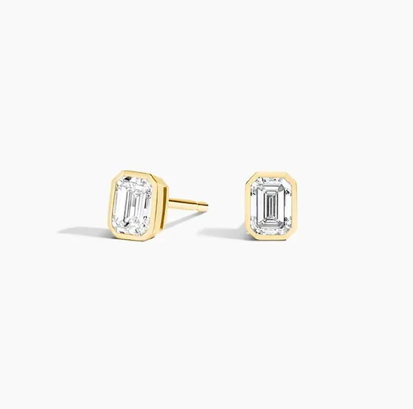 Pair of yellow gold stud earrings with rectangular clear stones in raised bezel-style settings.