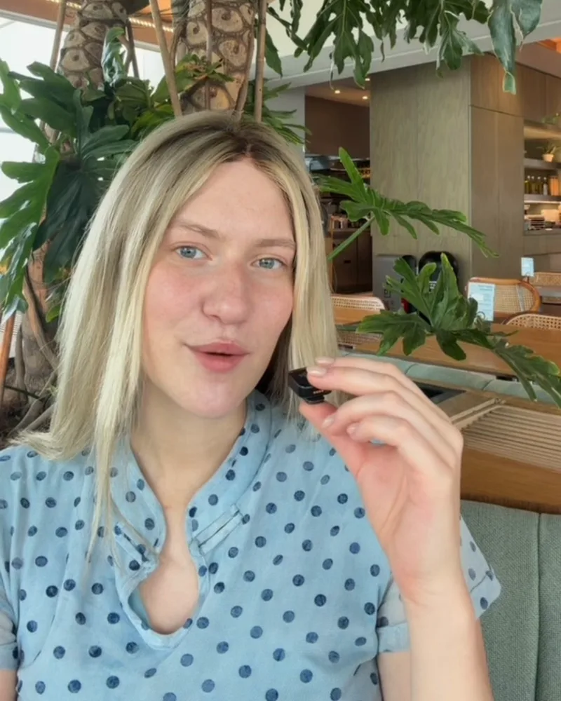 Ksenia Enbom speaking to the camera, wearing a blue shirt with dark dots