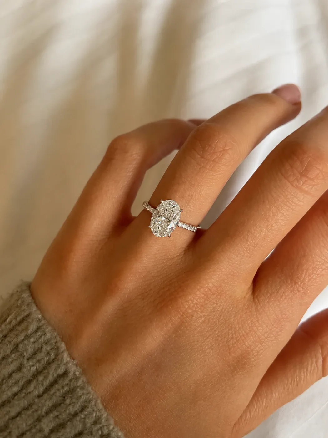 A small oval stone on a slim band, worn on a hand resting on a pale cloth