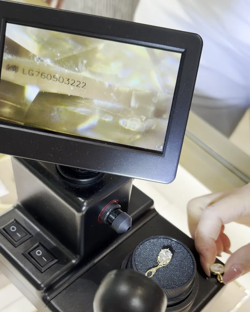 A screen showing a laser inscription number on a stone, above a holder with a stone and a ring